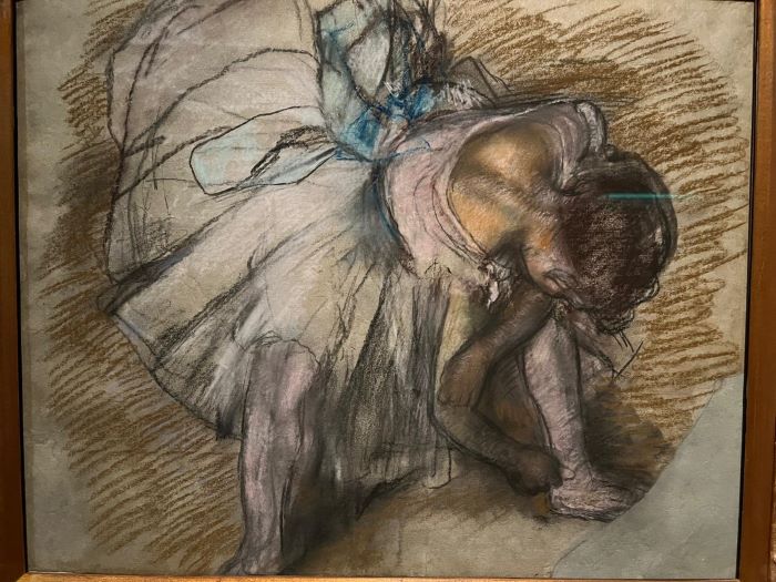disegno in carboncino e pastello di Edgar Degas. In quadratura dall'alto di una danzatrice connil tutù nell'atto di allacciarsi la scarpetta