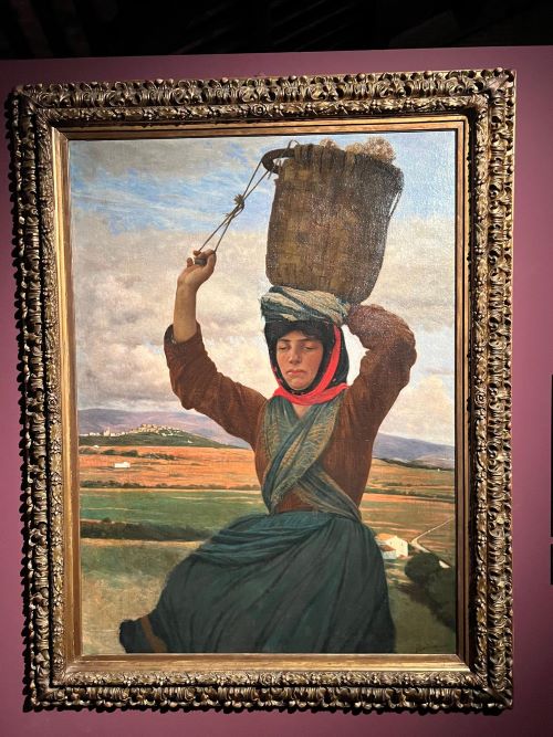 Un olio su tela di Federico Zandomeneghi nel suo periodo fiorentino e vicino al movimento artistico dei macchiaioli. Una giovane donna è la figura principale nella campagna toscana. Il suo viso è colorato dal sole e porta sulla testa una cesta di vimini